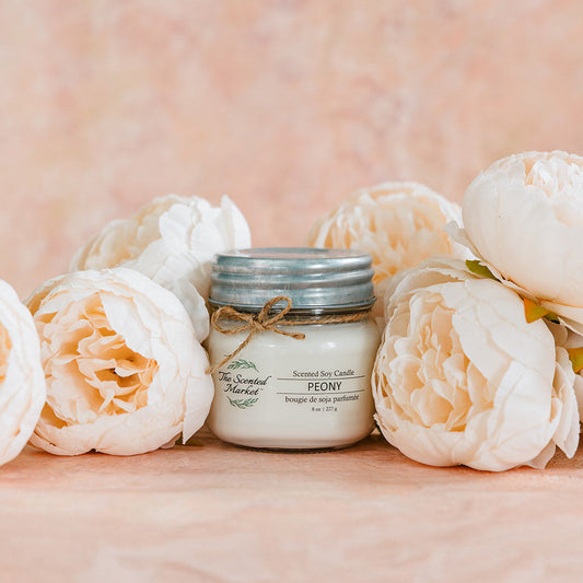 Jar of cream with a decorative string surrounded by white flowers on a soft pink background
