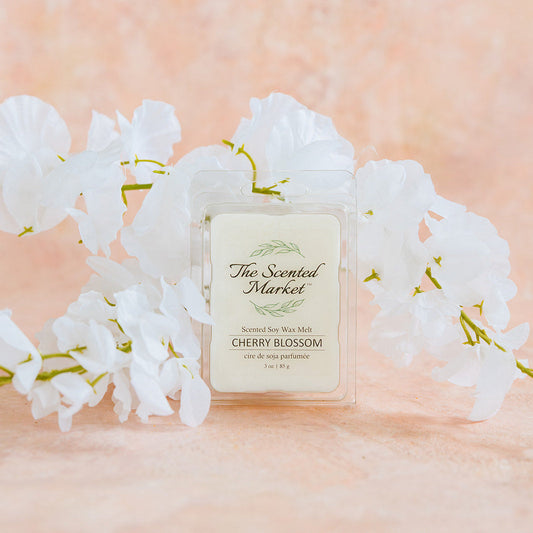 Perfume bottle labeled 'Cherry Blossom' by 'The Scented Market' with white flowers on a soft pink background