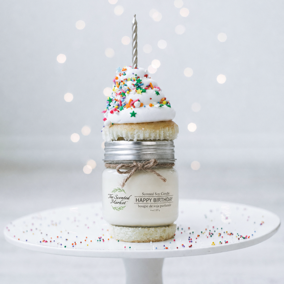 Decorative candle with a small cake on top and sprinkles, featuring 'The Scented Market' branding.