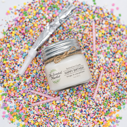 'Happy Birthday' labeled candle from The Scented Market laying on a pile of rainbow sprinkles