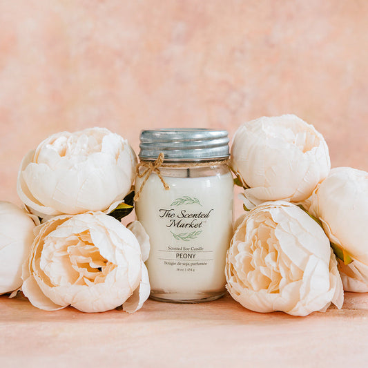 Candle with floral arrangement on a soft pink background